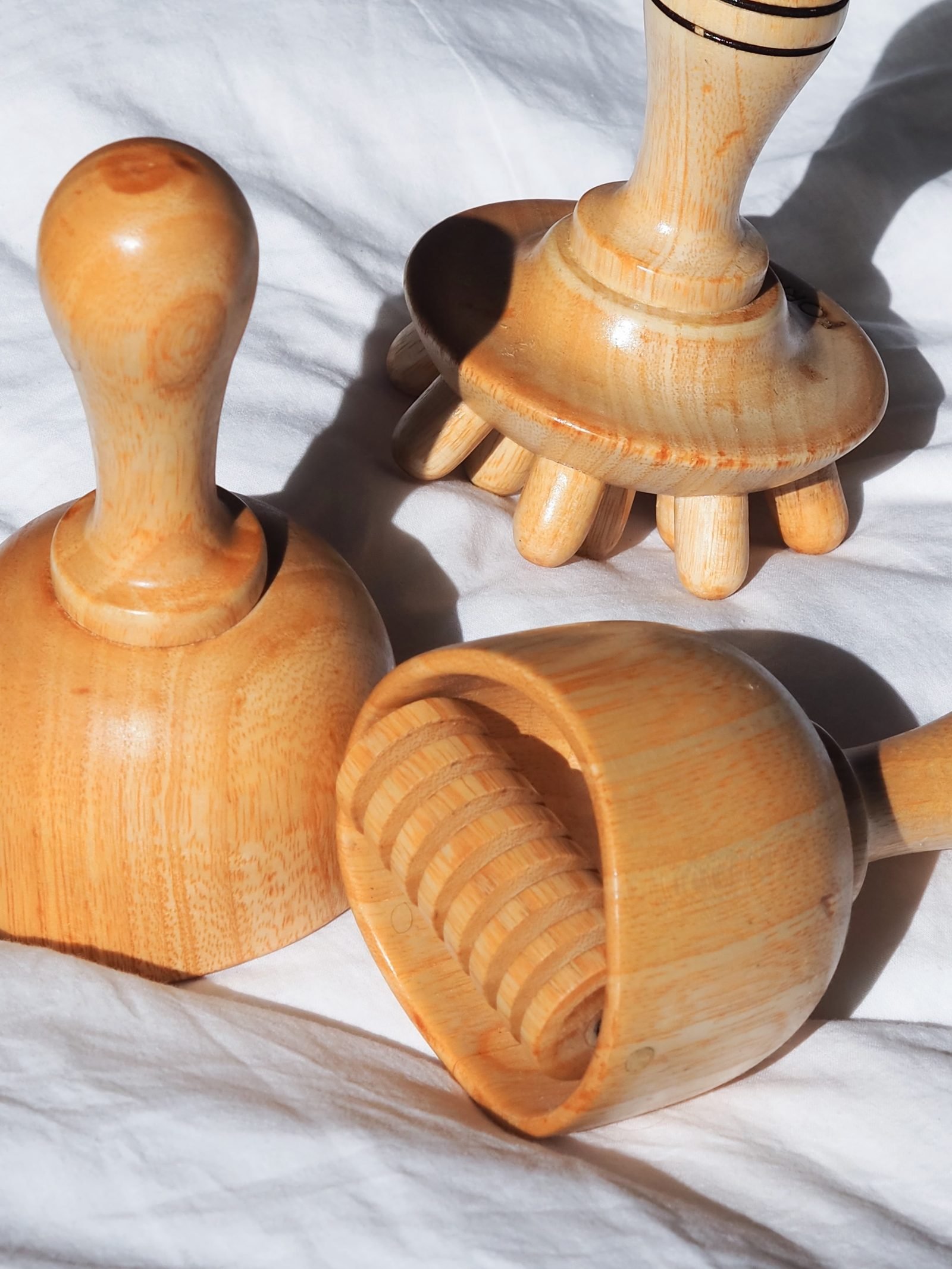 Outils de madérothérapie en bois posés sur un drap blanc, en lumière naturelle